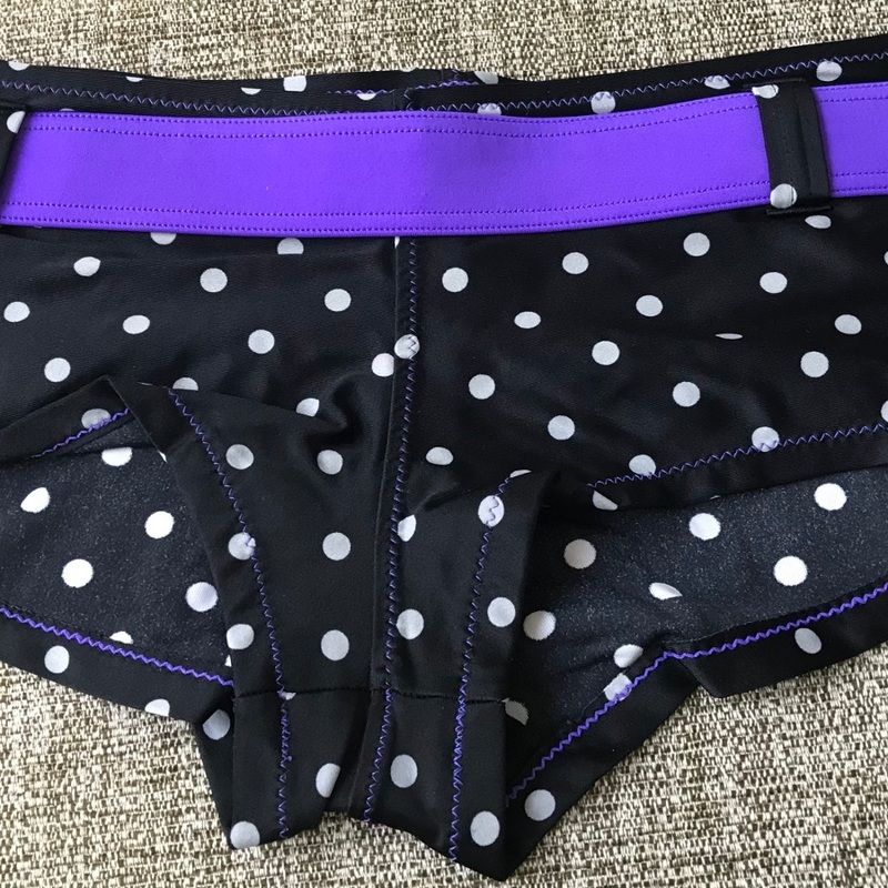 Retrotunnelmaa uimarannoille! Pisteelliset uimashortsit somistettu näyttävällä violetilla vyötärönauhalla. Pirteä uima-asu koossa M.